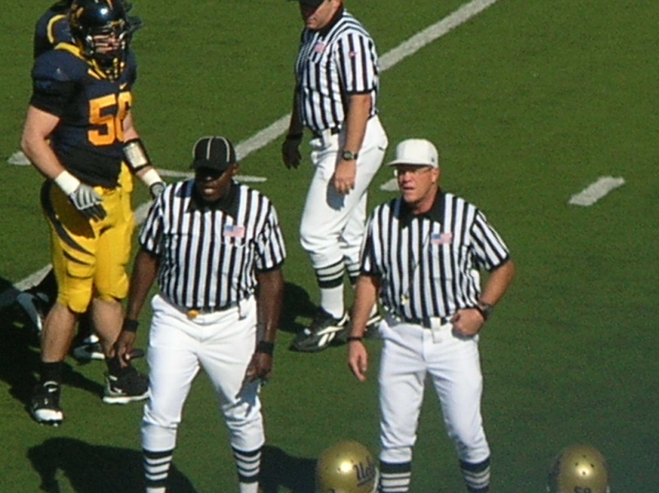 An American football referee in a white cap announces a penalty call during UCLA at California in 2008.