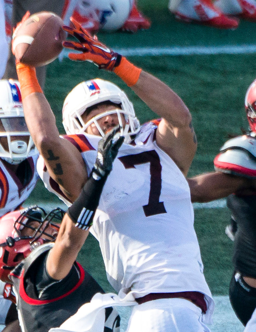Bucky Hodges in a white Virginia Tech uniform catches a football between defenders during the 2014 Military Bowl