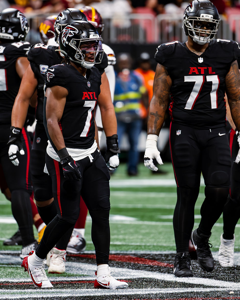 Bijan Robinson in Atlanta Falcons No. 7 running behind teammate Elijah Wilkinson against Washington on September 28, 2025.