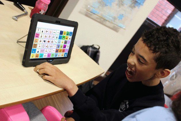 Boy using high tech PODD on device