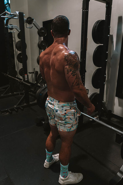 a shirtless man is lifting a barbell in a gym