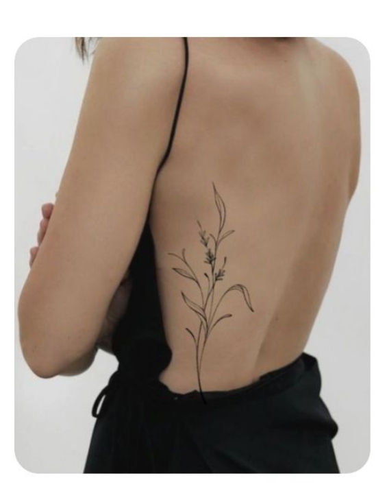 Costas de mulher com vestido preto e tatuagem floral fina na lateral, em fundo branco minimalista.