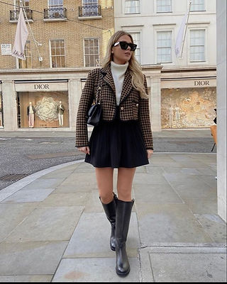 Mulher com casaco tweed, mini saia preta e bota cano longo