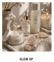 Produtos de skincare minimalistas em bandeja de mármore com vela acesa, sérum facial, creme hidratante e roller de quartzo rosa em estética elegante e aconchegante.