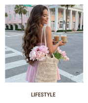 Mulher elegante com vestido rosa segurando cafés e flores em rua charmosa, transmitindo estética feminina, delicada e lifestyle sofisticado.