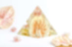 Pyramid resin preservation with florals and pink-orange hues, surrounded by dried flowers on a white background.