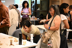 Two women at a team building event appreciating each other's creations, smiling and leaning over the table to look closer