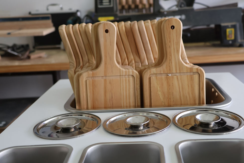 A set of handmade chopping boards lined up in their specific storage area on top of the catering cart