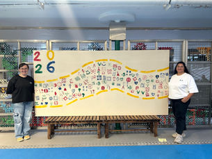 A picture of the two founders standing next to a large canvas of students' wood block prints