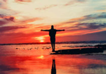Person standing on edge of lake at sunset