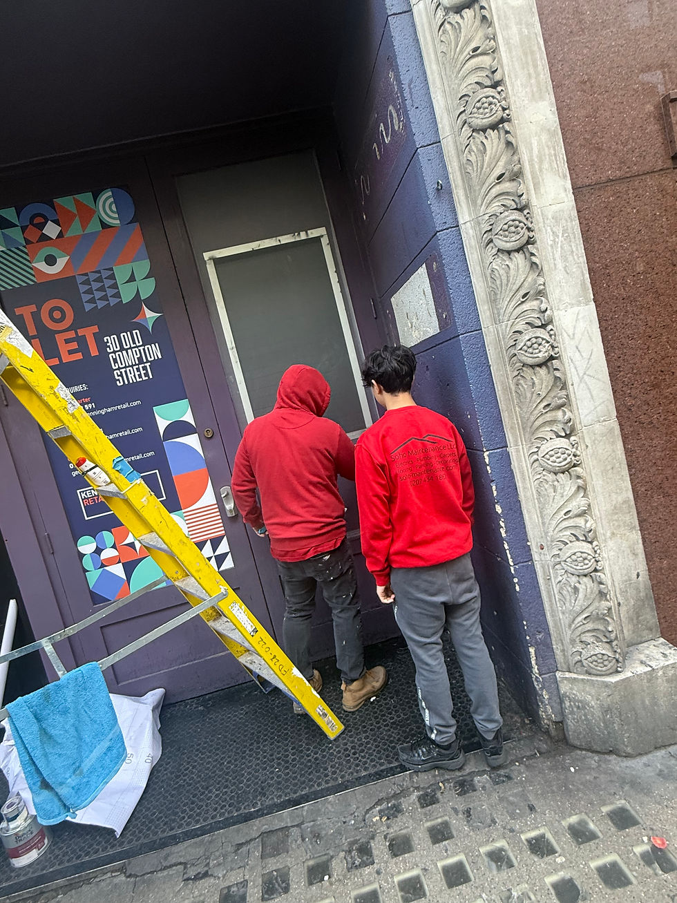 Two Soho Maintenance applying frosted film by building with 'TO LET' sign
