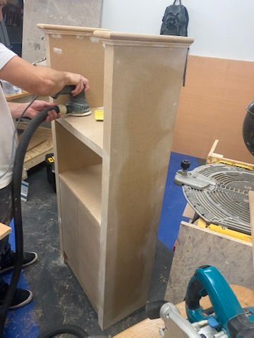 Soho Maintenance Ltd worker sanding a wooden cabinet