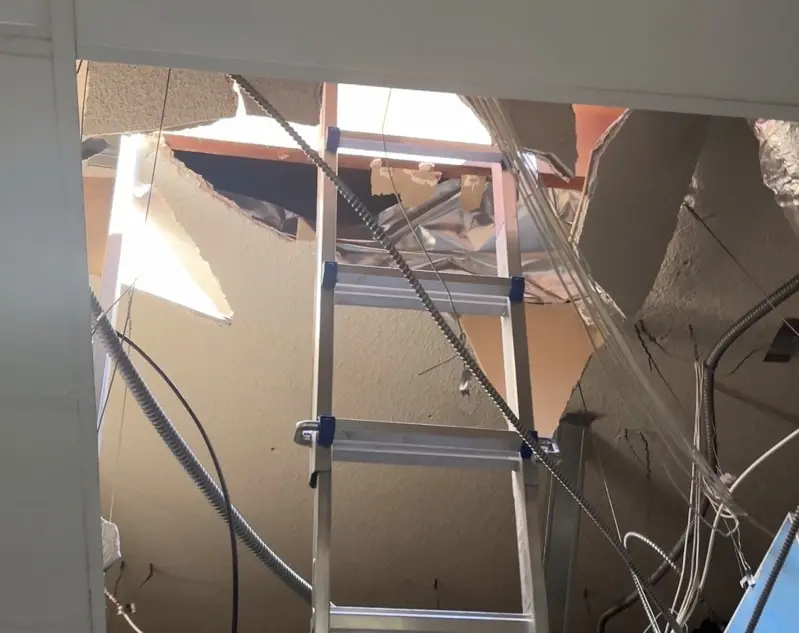 隔壁原是間奶茶店,半個月前剛搬走,而屋頂竟出現一個巨大的破洞,有梯子垂下來。(李女士提供世界日報)