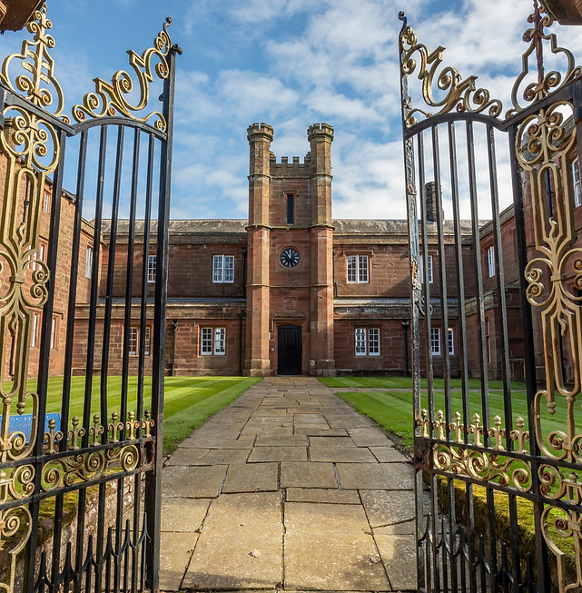 Ornate gates opening to a historic building in the UK.