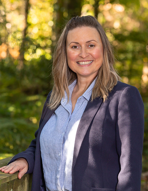 Professional headshot photography of a smiling woman in a forest.