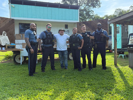 A man standing with police officers in front of a market stand on a farm