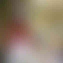 A woman wearing a brown sweater smiling standing near a garden gate