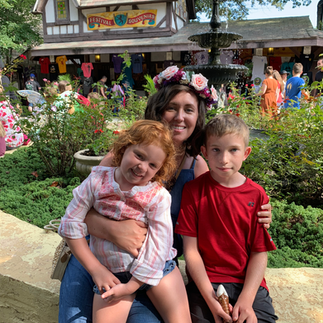 A woman and two children sitting together at a fountain smiling