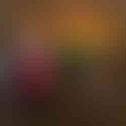 A man and a woman in Halloween costumes stand in front of a spooky photo op that is built to look like a witch's hearth and cauldron