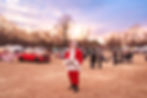Santa standing in the middle of an outdoor market at sunset
