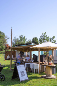 An outdoor market stand where a family speaks to a woman behind the counter