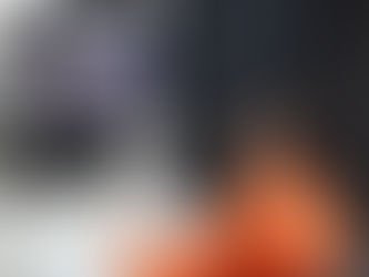 Eine Person mit einem orangenen Pullover schaut auf einen Bildschirm und baut etwas nach.