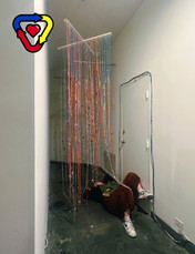 Person laying under an art installation of string and beads. 