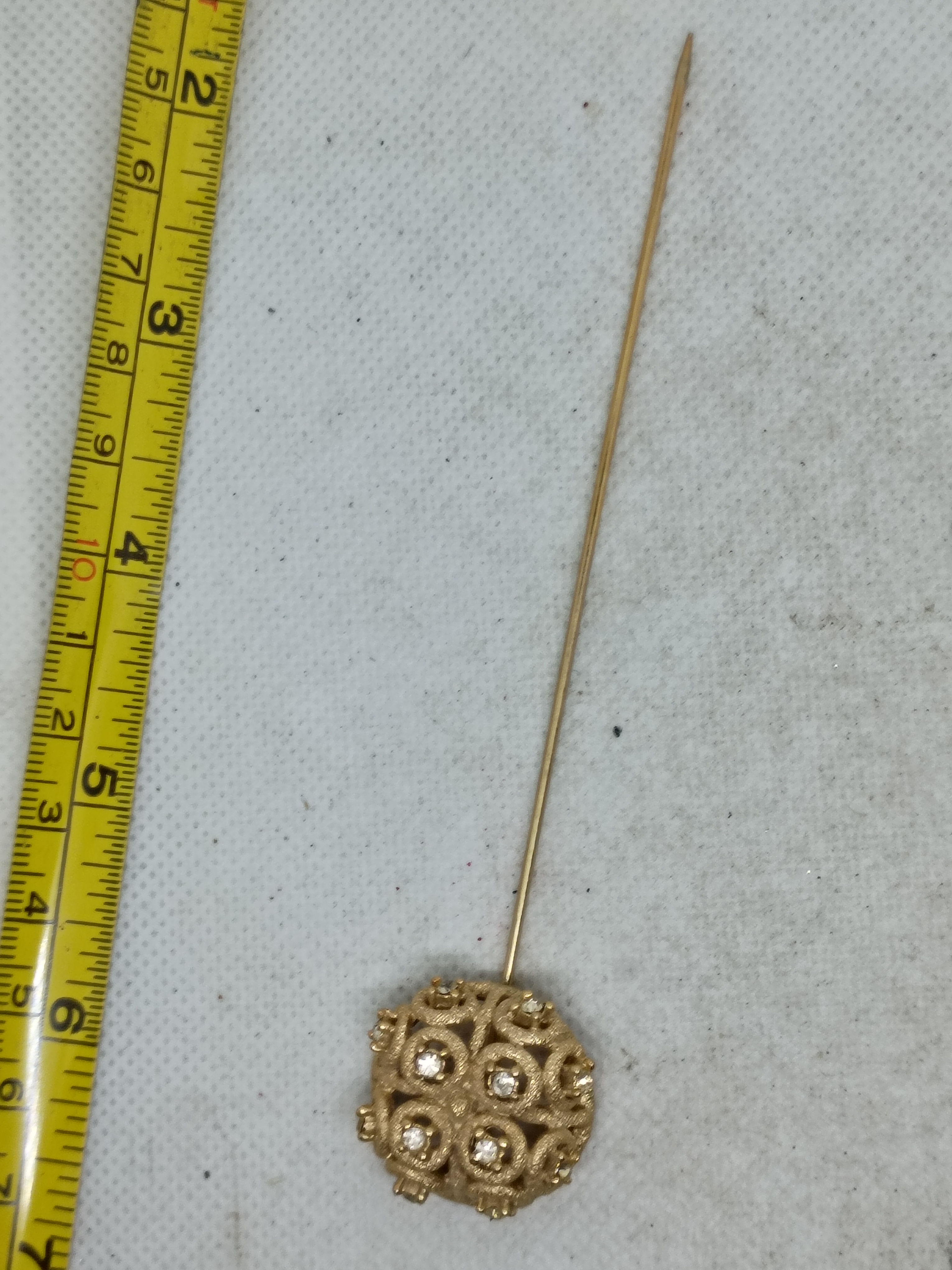 This is an ornate, textured gold-tone sphere head of a vintage hat or lapel pin