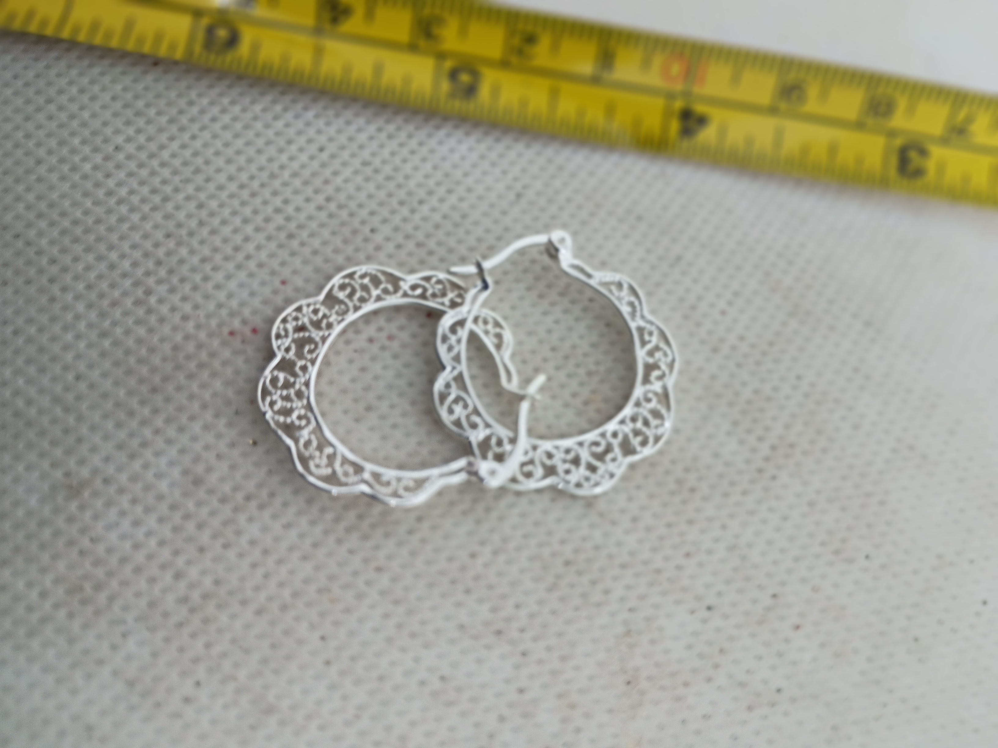 1" silver-plated hoop earrings feature an intricate openwork filigree pattern