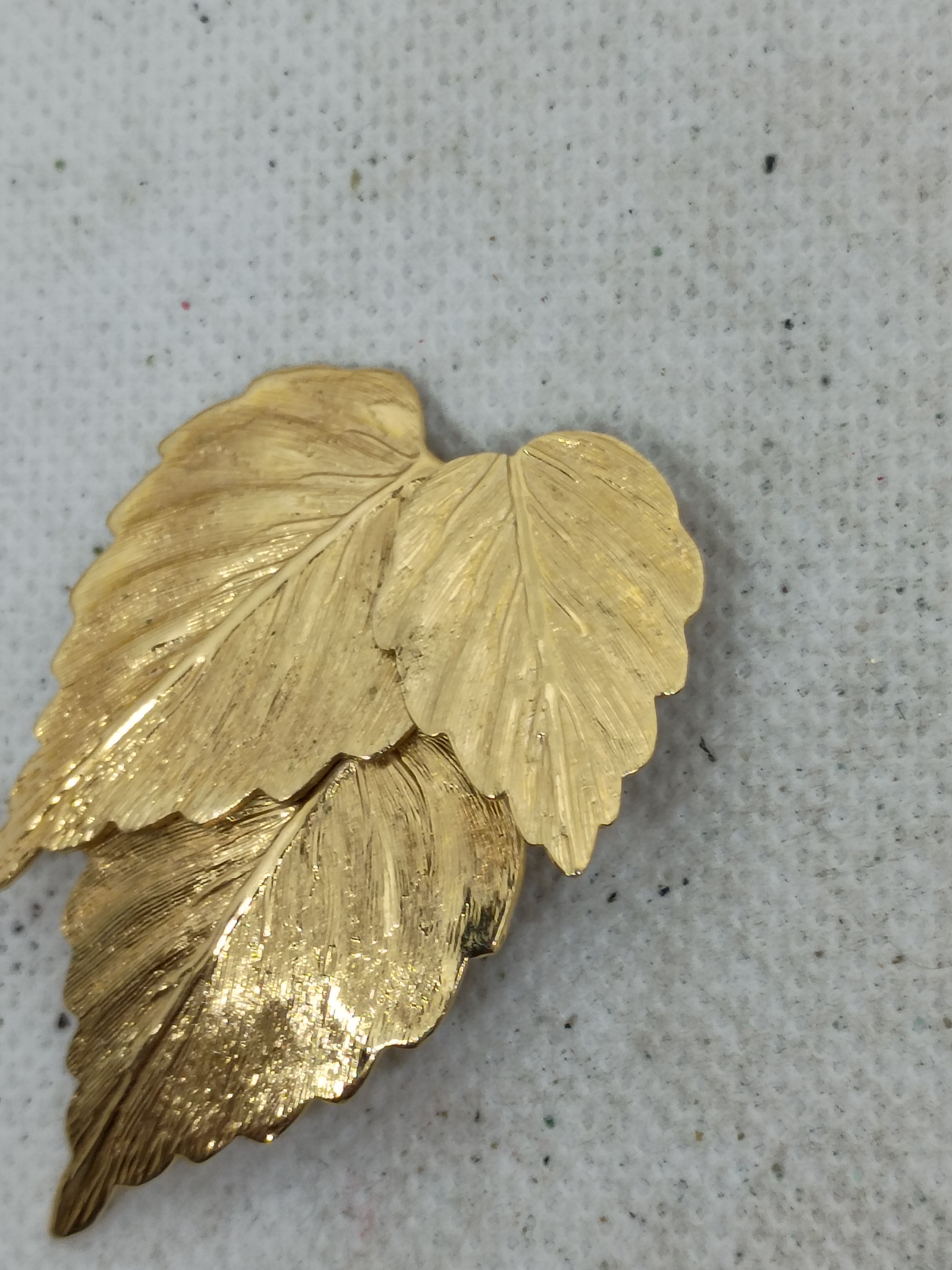 Vintage textured triple-leaf cluster brooch features a brushed gold-tone finish