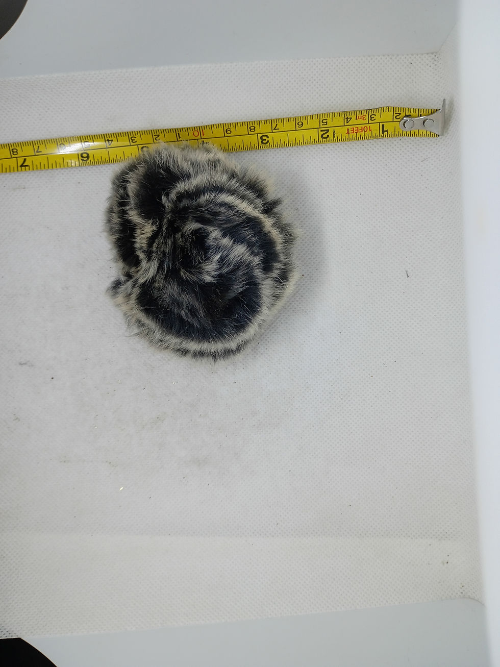 Thumbnail: 4" A decorative flower brooch or hair accessory made of black and white fur