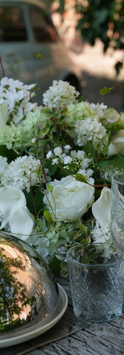 Centerpiece van witte bloemen voor een huwelijk. Het bestaat uit witte rozen, gipskruid, aronskelken en hortensia's. Het is om te plaatsen op een tafel tijdens een huwelijk om op te vallen. Op de foto is staat ook een cloche voor eten en een fiat 500