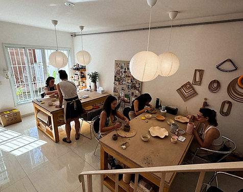 Grupo modelando argila na mesa grande do Arya Studio