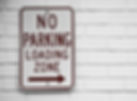 No Parking Loading Zone sign on white brick wall