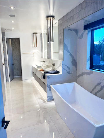 beautiful all quartz bathroom tiled walls, floors, and double sink with full glass shower and white bathtub