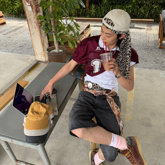 man with red jersey and black jorts sitting and drinking coffee