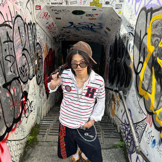 Man with glasses, striped shirt, and black jorts looking at camera