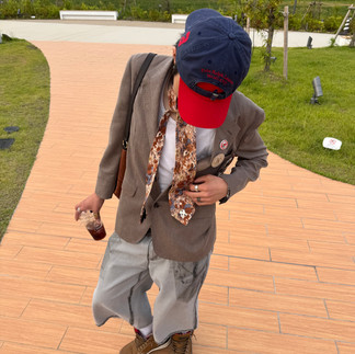 Man with brown coat and grey jorts posing