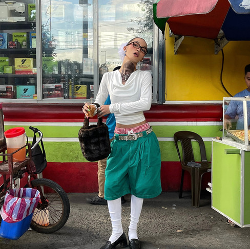 Girl with white long sleeve shirt and teal pants posing for camera while holding abg