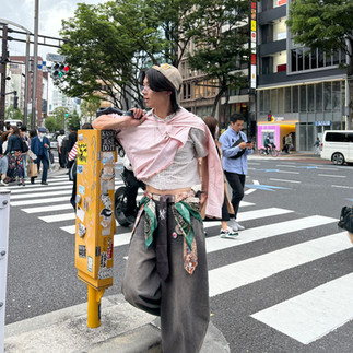 man with pink shirt grey jean leaning against a pole