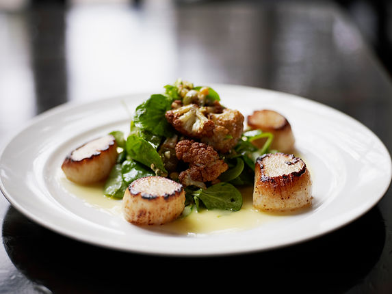 Signature scallop dish plated nicely on a plate