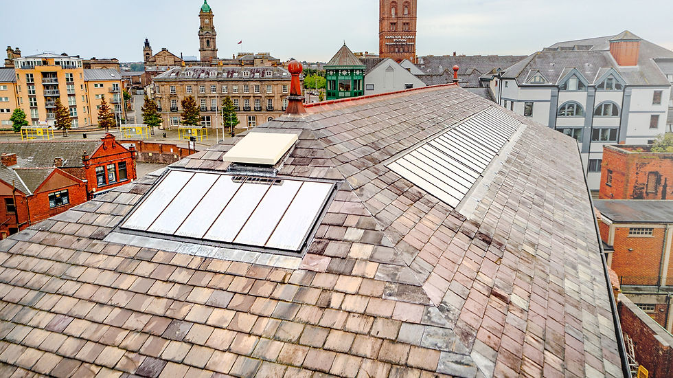 Slate rooftop with skylights overlooking a town skyline; Hamilton Square Station sign visible on a brick tower.