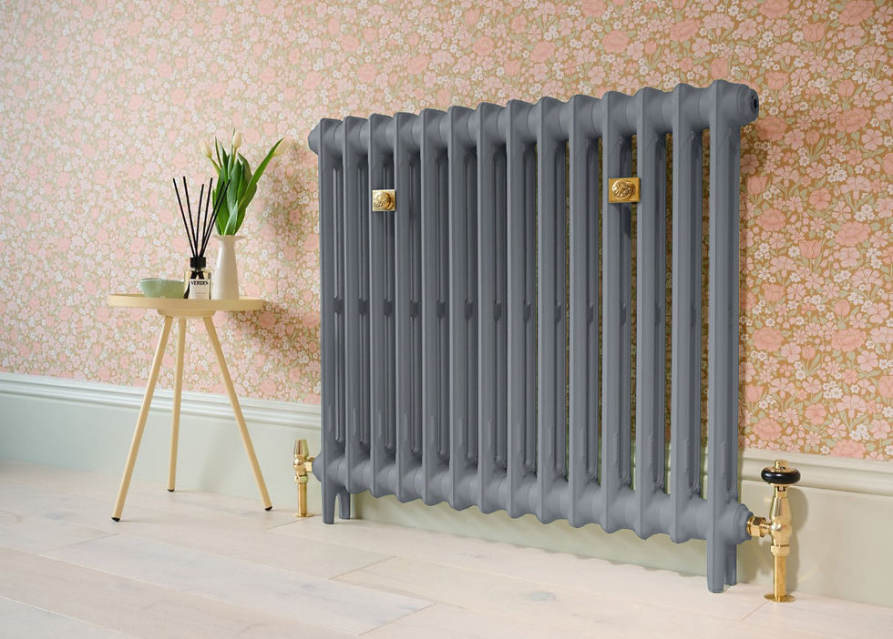 Gray radiator against pink floral wallpaper. Beige table holds a vase with tulips and a diffuser labeled "VEDDY," on light wood floor.