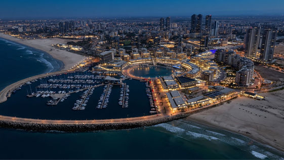 Illuminated city marina with yachts and buildings at night
