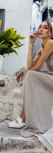 Beautiful model in Mediterranean dress and headband poses for natural light photoshoot in greece at golden hour