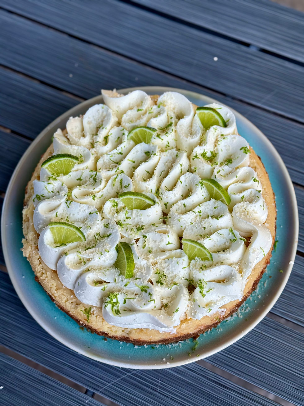 Gâteau au citron vert (Key Lime Pie) sur une assiette bleue, décoré de crème blanche, zestes verts et quartiers de lime sur table sombre.