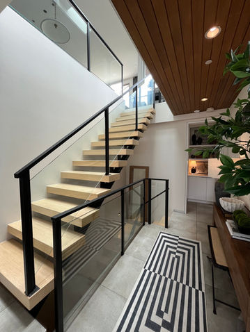 Glass staircase with black posts and hand rails.