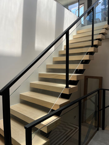 Glass staircase with black posts and hand rails.