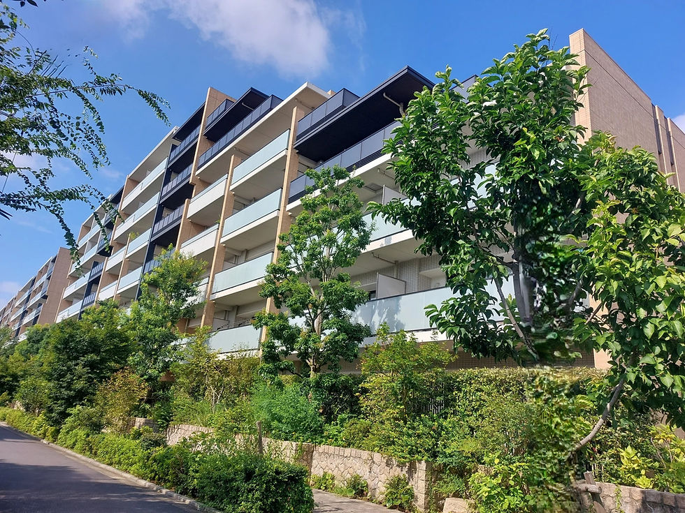 青空の下、木々に囲まれたモダンな集合住宅の庭園。