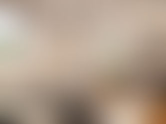 Chambre élégante avec fauteuil beige, lustre sphérique, miroir rond. Lit avec plaid noir et blanc. Fenêtres ouvertes sur un jardin. Ambiance paisible.